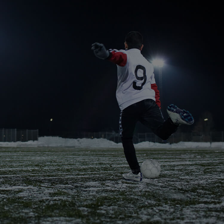 Ragazzo che gioca a calcio in inverno con la neve