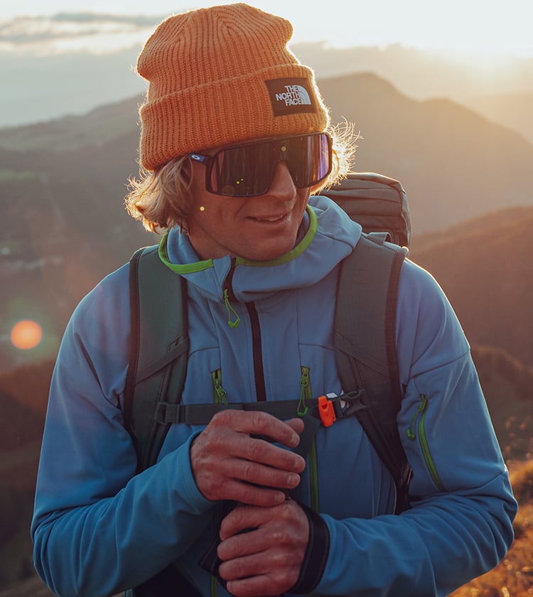 Ragazzo in montagna con occhiali da sole e vestito outdoor