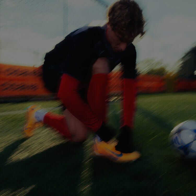 Ragazzo che si allaccia le scarpe da calcio Nike in campo