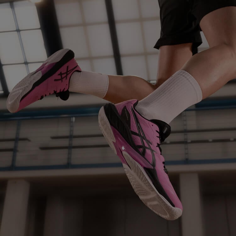 Ragazza che indossa paio di scarpe da pallavolo rosa brand Asics
