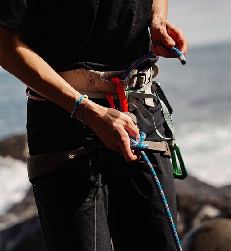 Ragazzo che fa alpinismo, vista mentre che sta indossando imbragatura di sicurezza